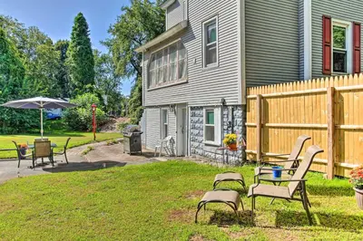 a yard with chairs and an umbrella next to a house at Cozy Agawam Studio with Yard 2 Miles to Six Flags! in Agawam
