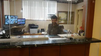 a man standing behind a counter in a kitchen at Flushing Motel in Queens