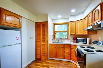 a kitchen with wooden cabinets and a white refrigerator at Mountain Top Country Hideaway 48 Acres, Fire Pit! in Leonardsville