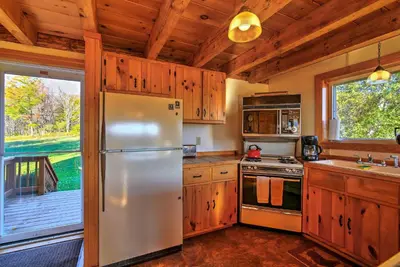 a kitchen with a stainless steel refrigerator and a porch at Bearpen Lodge on 125 Acres - Near Belleayre Mtn! in Vega