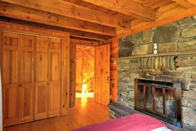 a living room with a fireplace and a stone wall at Bearpen Lodge on 125 Acres - Near Belleayre Mtn! in Vega