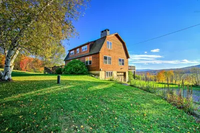 a large wooden house on a hill next to a lake at Bearpen Lodge on 125 Acres - Near Belleayre Mtn! in Vega