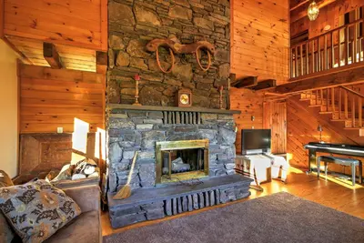 a living room with a stone fireplace and a piano at Bearpen Lodge on 125 Acres - Near Belleayre Mtn! in Vega