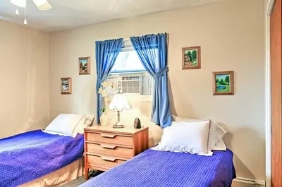 a bedroom with two beds and a window with blue curtains at Mayfield Home with Private Dock on Lake Sacandaga! in Broadalbin