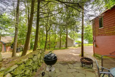 a grill sitting next to a stone wall next to a house at Rustic Berkshires Cottage at Lake Buel with Kayaks! in New Marlborough