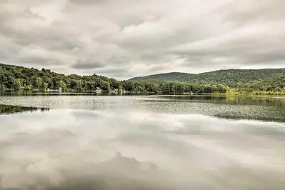 a large body of water with trees and clouds at Rustic Berkshires Cottage at Lake Buel with Kayaks! in New Marlborough