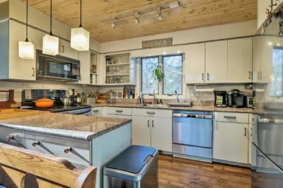 a large kitchen with white cabinets and blue appliances at Peaceful Goshen Cottage with Screened Porch and Views! in Goshen