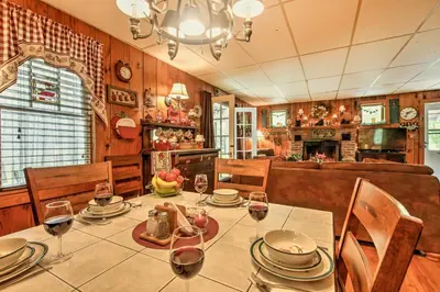 a dining room with a table with plates and wine glasses at Pet-Friendly Cabin with Fire Pit, BBQ and Great Deck! in Williamsburg