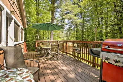 a wooden deck with a grill and an umbrella at Pet-Friendly Cabin with Fire Pit, BBQ and Great Deck! in Williamsburg