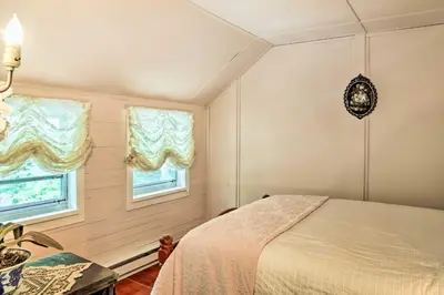 a bedroom with a bed and two windows at Authentic 1912 Adirondack Lake Camp with Fire Pit in Stratford