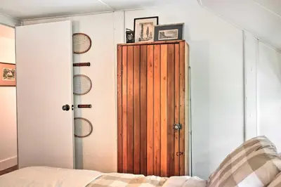 a bedroom with a wooden door next to a bed at Authentic 1912 Adirondack Lake Camp with Fire Pit in Stratford