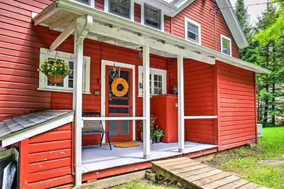 a red house with a red door and a porch at Authentic 1912 Adirondack Lake Camp with Fire Pit in Stratford