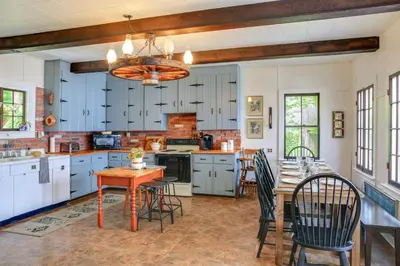 a kitchen with blue cabinets and a table and chairs at Authentic 1912 Adirondack Lake Camp with Fire Pit in Stratford