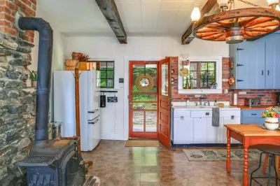 a kitchen with a fireplace and a stove at Authentic 1912 Adirondack Lake Camp with Fire Pit in Stratford