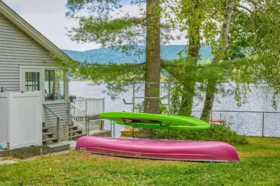 a green and pink trampoline in the grass next to a house at Massachusetts Lake House with Dock - Pets Welcome! in New Marlborough
