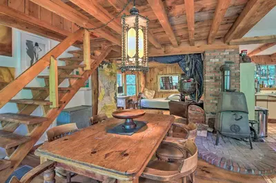 a dining room with a wooden table and a staircase at Berkshire Riverfront Ski Cabin Close to Hiking! in Mill River