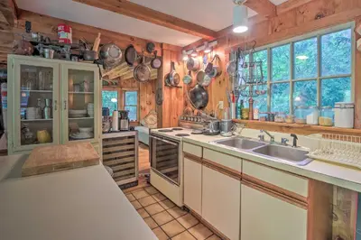 a kitchen with wooden walls and a sink and windows at Berkshire Riverfront Ski Cabin Close to Hiking! in Mill River