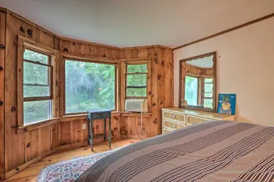 a bedroom with wooden walls and a bed and windows at Berkshire Riverfront Ski Cabin Close to Hiking! in Mill River