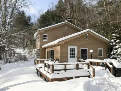 a house covered in snow in front of it at Berkshire Riverfront Ski Cabin Close to Hiking! in Mill River