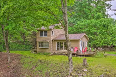 a house with a deck and chairs in the yard at Berkshire Riverfront Ski Cabin Close to Hiking! in Mill River