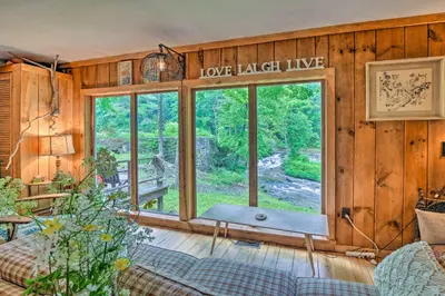 a living room with a large window and a couch at Berkshire Riverfront Ski Cabin Close to Hiking! in Mill River