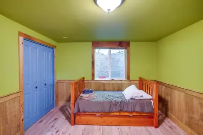 a bed in a room with green walls and a window at 4 Mi to Mount Snow West Dover Cabin with Game Room in West Dover