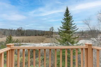a wooden fence with a pine tree behind it at Spacious Condo with View Less Than 1 Mi to Mtn Creek Resort! in Vernon Township