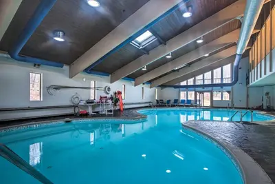 a large swimming pool with blue water in a building at Pocono Mountain Home with 3 Community Lakes! in Gouldsboro