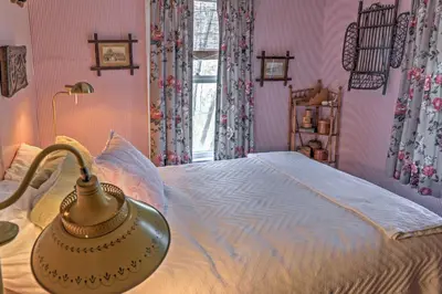a bedroom with a bed with pink walls at Dainty New Preston Cottage with Dock and Lake Views! in New Preston