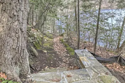 a stone path in the woods next to a tree at Dainty New Preston Cottage with Dock and Lake Views! in New Preston