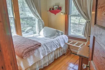 a small bedroom with a bed and two windows at Dainty New Preston Cottage with Dock and Lake Views! in New Preston