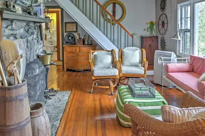 a living room with chairs and a stone fireplace at Dainty New Preston Cottage with Dock and Lake Views! in New Preston