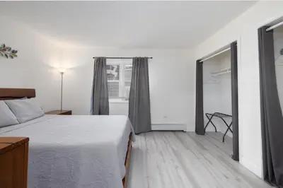 a white bedroom with a bed and a window at Chic with Recliner at Webster Hill Suite 1W Request Xtra Bed in New Britain