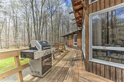 a grill on a deck next to a house at Walk to Big Bass Lake Family Home with Deck! in Gouldsboro