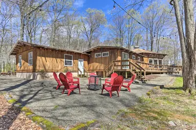 a group of red chairs in front of a log cabin at Walk to Big Bass Lake Family Home with Deck! in Gouldsboro