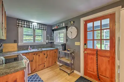 a kitchen with wooden cabinets and a clock on the wall at Charming Wilmington Cabin, 8 Mi to Mt Snow! in Wilmington