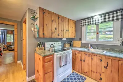 a kitchen with wooden cabinets and a stove top oven at Charming Wilmington Cabin, 8 Mi to Mt Snow! in Wilmington