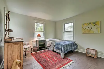 a bedroom with a bed and a table and two windows at Millburn House with Deck - Walk to NYC Transit! in Millburn