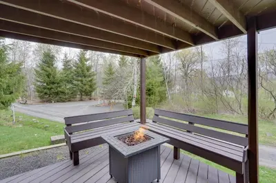 a screened porch with two benches and a fire pit at Catskills Home, 5 Mins to Windham Mtn Resort! in Windham
