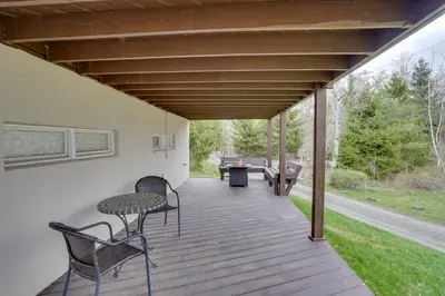 a wooden deck with chairs and tables on it at Catskills Home, 5 Mins to Windham Mtn Resort! in Windham