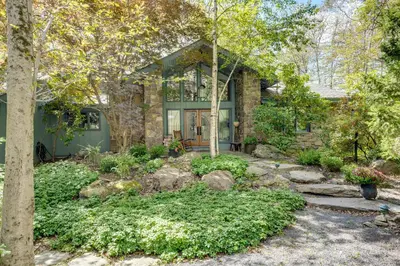 a stone house with a garden in front of it at Luxe Poconos Pines Home with Beach and Amenities! in Pocono Pines