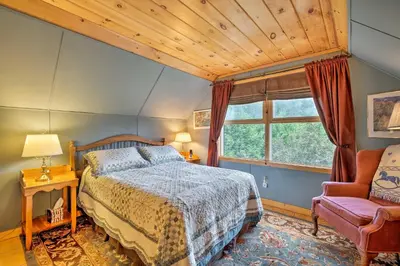 a bedroom with a bed and a chair and a window at Jacksonville Cabin with Wraparound Deck and Views in Jacksonville