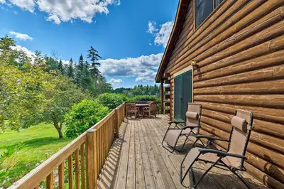 a wooden deck with chairs and a table on a house at Jacksonville Cabin with Wraparound Deck and Views in Jacksonville