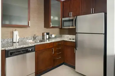a kitchen with wooden cabinets and a stainless steel refrigerator at Residence Inn by Marriott Springfield Chicopee in Chicopee