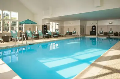 a large swimming pool with chairs and an umbrella at Residence Inn by Marriott Springfield Chicopee in Chicopee