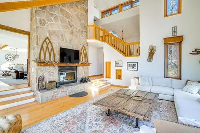 a living room with a large stone fireplace at Wilmington Retreat with Deck, Lake Views and Game Room in Wilmington