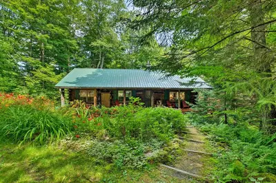 a house with a green roof in the woods at Private Wooded Cabin 7 Mi to Mount Snow! in Wilmington