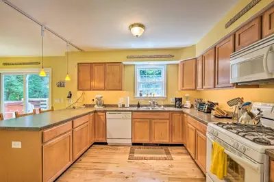 a large kitchen with wooden cabinets and a sink at West Dover Home with Deck, Grill and EV Outlet in West Dover