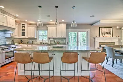 a kitchen with white cabinets and a large island with bar stools at West Dover Home - 3 Miles to Mount Snow Resort! in West Dover