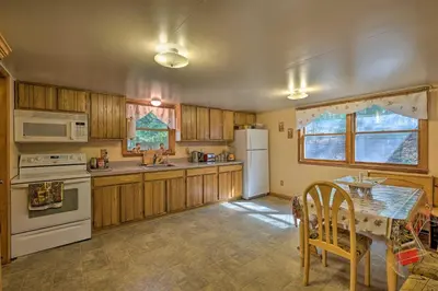 a kitchen with wooden cabinets and a white refrigerator at Catskill Mtn Home with Deck about 1 Miles to Zoom Flume! in East Durham
